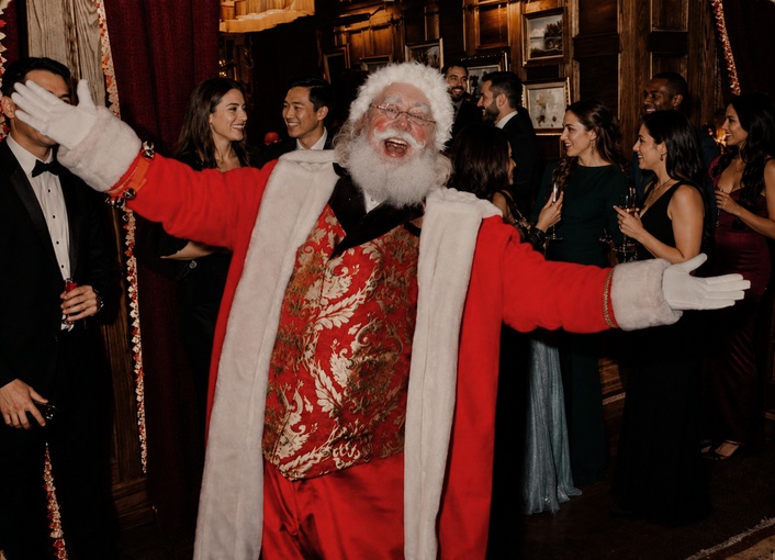 Santa James making a joyful entrance at an event with arms open wide.
